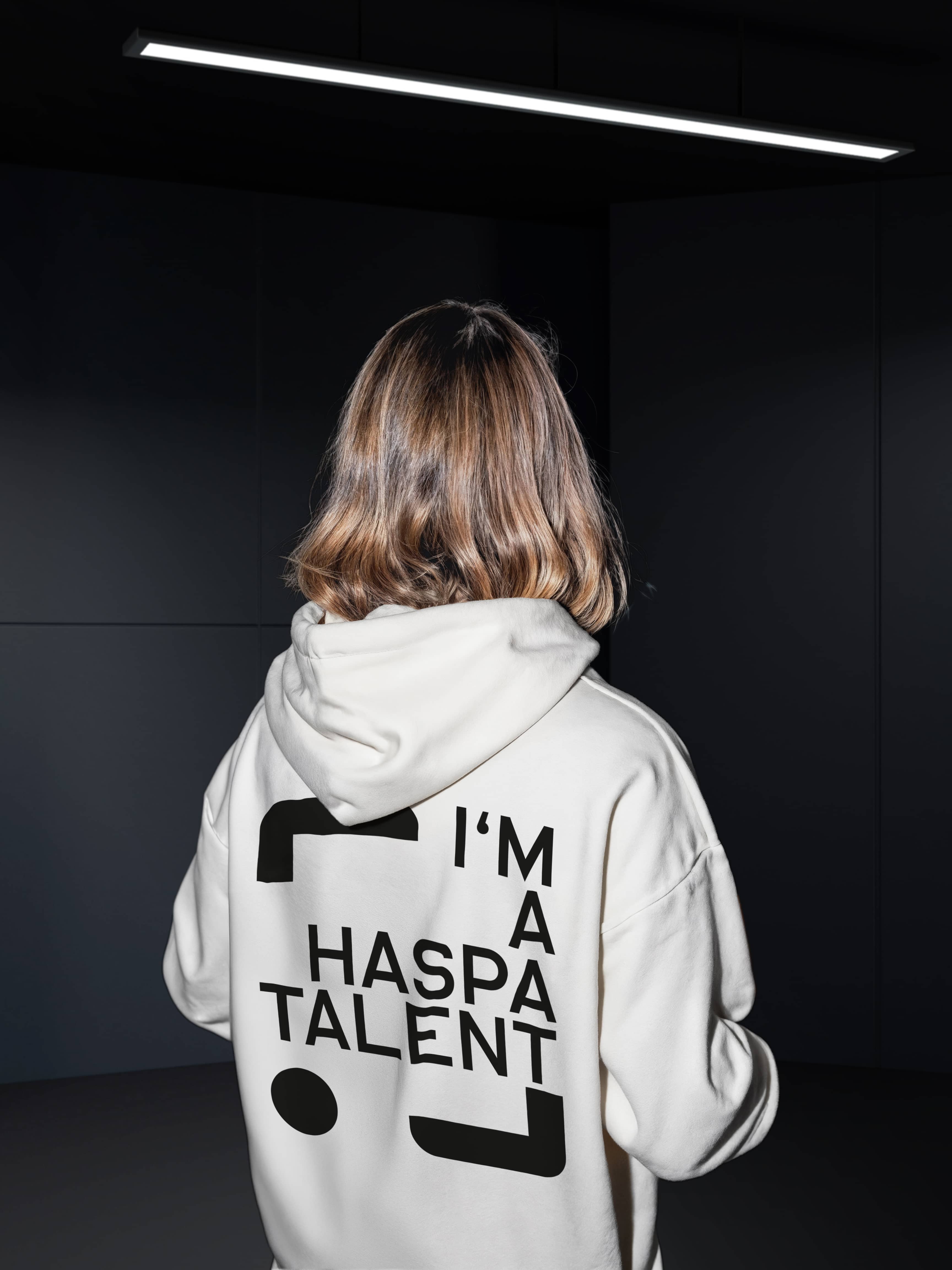 Eine junge Frau wendet der Kamera den Rücken zu. Auf ihrem Pullover ist das Logo der Hamburger Sparkasse zu sehen.